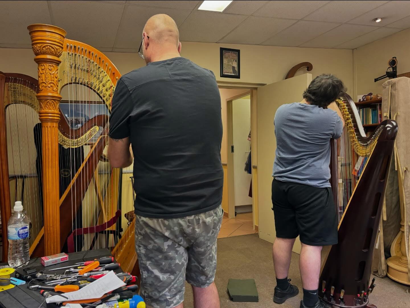 Two technicians regulating pedal harps in a workshop